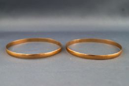 A set of two yellow metal D shape bangles. Polished finish. 65.0mm diameter.