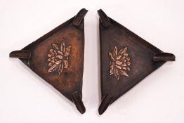 An Arts and Crafts pierced and embossed copper round wall plate and a pair of copper triangular