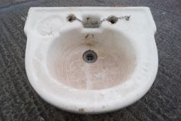 A glazed stoneware wash hand basin of half round form, set with an indented soap reserve,