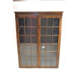 A pair of walnut standing display cabinets with two glazed doors,