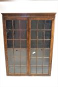 A pair of walnut standing display cabinets with two glazed doors,