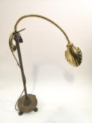 A brass desk lamp with shell shaped shade on round base with paw feet,