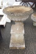 A pair of composite garden urns on pedestals,
