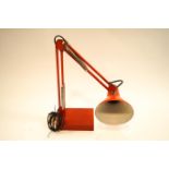 A red anglepoise lamp with rectangular base,