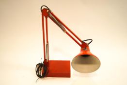 A red anglepoise lamp with rectangular base,