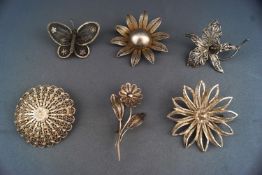 A collection of six white metal brooches of variable designs having pierced filigree finish.