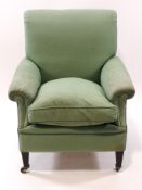 An Edwardian armchair upholstered in green with one loose cushion on square tapering legs