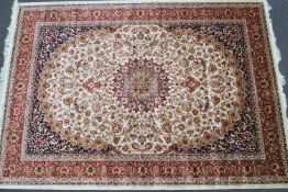 A machine woven Keishan style carpet with central medallion issuing scrolling flowers on a beige
