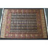 A machine woven Bokhara style carpet with thirteen rows of medallions on a blue ground within