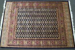 A machine woven Bokhara style carpet with thirteen rows of medallions on a blue ground within
