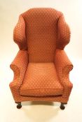 An upholstered wing back armchair on mahogany cabriole legs