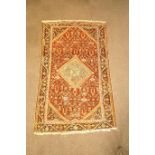 A rug with central medallion on an overall patterned red field within one wide border,