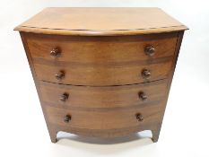 A 19th century commode, the bow front opening with four faux drawers and turned handles,