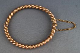 A yellow metal twisted bangle with push in clasp and safety chain.