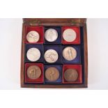 A wooden case containing nine assorted metal sporting prize medals fencing, long jump,