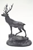 A Mene bronze sculpture of a stag, standing facing left on a rocky outcrop,