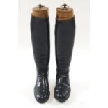 A pair of gentleman's black leather riding boots and wooden lasts with brass ring pull handles,