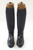 A pair of gentleman's black leather riding boots and wooden lasts with brass ring pull handles,