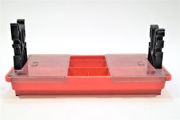 A rifle cleaning stand in red and black plastic, 26 cm high (max), 59 cm wide, and 28 cm deep.