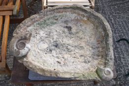 A carved stone bird bath with fossils exposed,