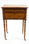 A 19th century birds eye maple side table with two drawers on turned legs with brass casters,