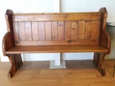 A late 19th century pine pew of plain form with planked back between shaped ends with quarter