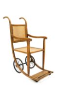An invalids chair, early 20th century, the oak and beech frame with caned seat and back,
