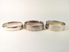 Three silver bangles to include; A silver buckle bangle, A silver half engraved bangle,