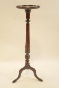 A mahogany torchere, the round top with beaded moulding,