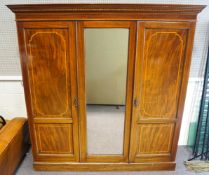 An Edwardian mahogany triple panelled wardrobe the panelled doors with satinwood cross banding