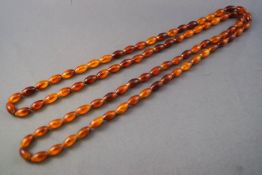 A single strand of oval orange beads. Strung plain omitting clasp.