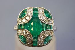 A white metal dress ring set with a central oval faceted cut emerald of approximately 1.00ct.
