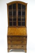 A walnut bureau bookcase with two glazed doors above a fall front above three drawers on bracket