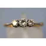 A yellow and white metal three stone diamond ring.