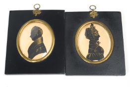 A pair of silhouettes of a lady and gentleman in late Regency dress,