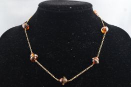 A yellow metal necklace consisting of half circle amber beads interspaced with rock crystal rondels.
