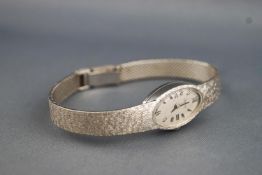 A white metal wristwatch by Zodiac. Oval case with silver dial and mixed markings.