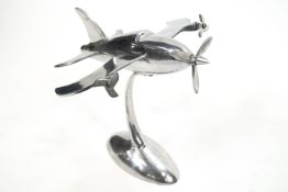 An aluminium aeroplane in the Art Deco style with three moving propellors, on an oval base,