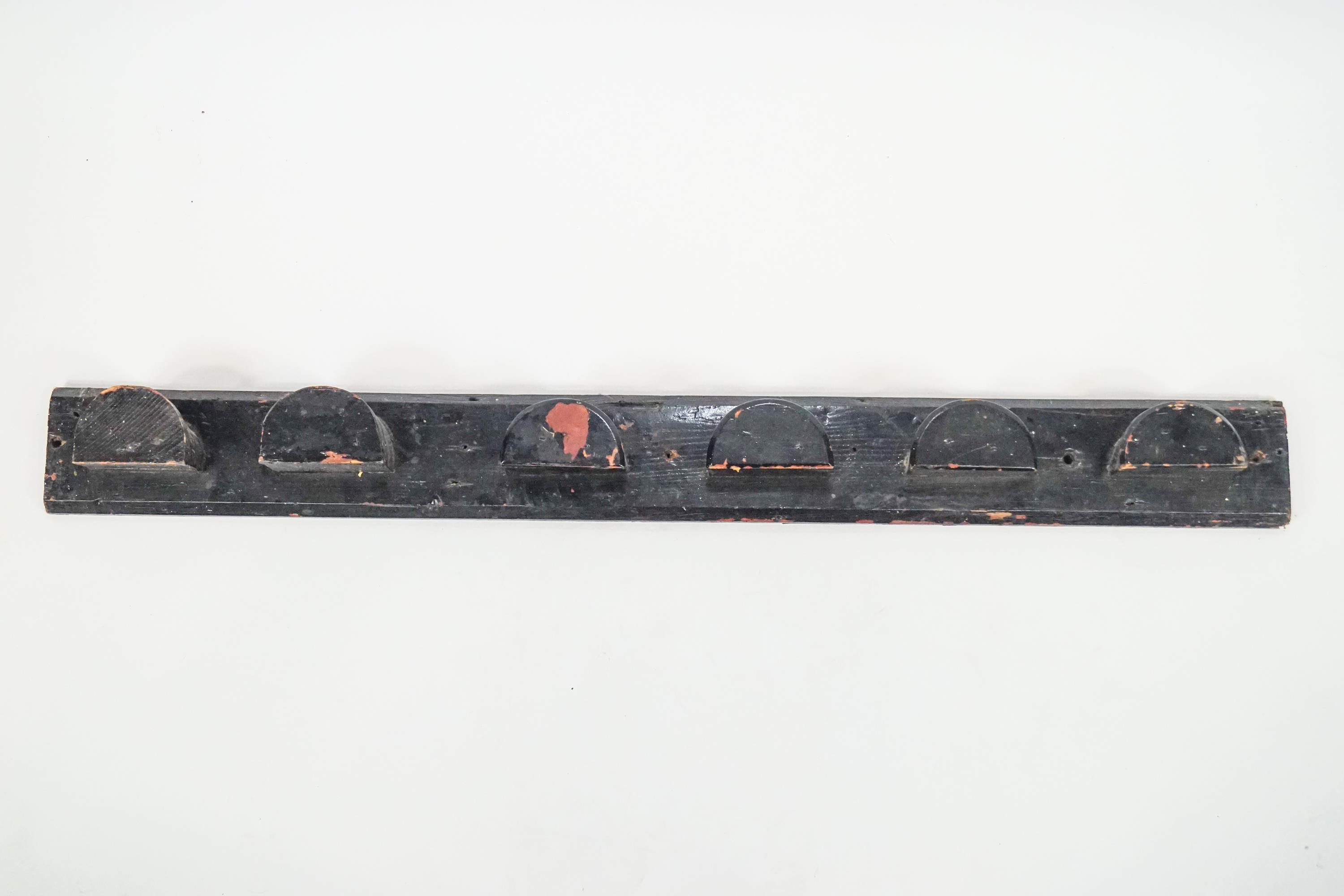 A 19th century mixed wood wall mounted Bridle rack for six bridles, over painted in black,