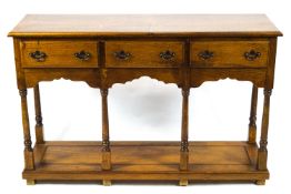 A George III style dresser with three drawers above a shaped apron on turned legs