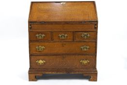 A George III oak bureau with fall front above three short drawers above two long drawers