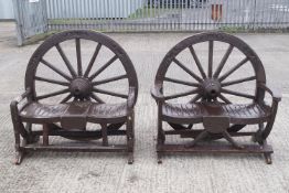 A pair of two seat garden benches, each with a cart wheel backs,
