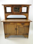 An oak Arts and Crafts style dresser, the raised back with lead glazed panelled door,