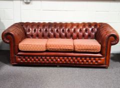 A leather two seat sofa, of Chesterfield form with three fabric upholstered seat cushions,