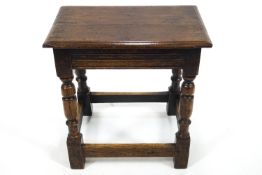 A 19th century oak joint stool on turned legs, linked by a stretcher,