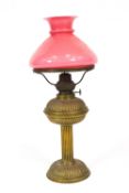 An early 20th century brass oil lamp, with pink overlay glass shade,