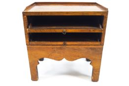 An 18th century style walnut book rack with two sliding shelves with shaped apron on square legs,