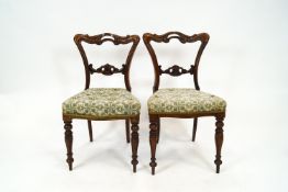 A pair of Victorian rosewood side chairs with carved and pierced backs and stuff over seats