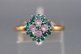 A yellow metal cluster ring set with four round faceted tanzanite and surrounded by treated blue