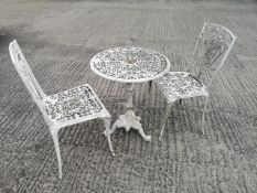 A cast metal round form garden table with pierced geometric patterning on a decorative baluster